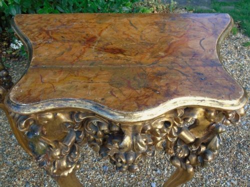 A pair of ornate Spanish giltwood console tables featuring deeply carved shell aprons and cabriole legs resting on scroll feet. View VIII