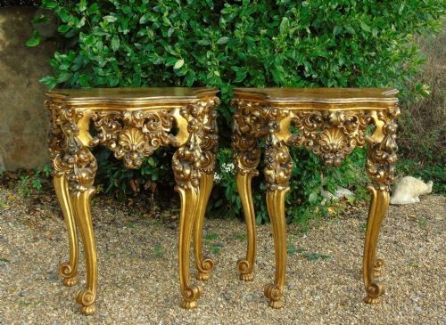 A pair of ornate Spanish giltwood console tables featuring deeply carved shell aprons and cabriole legs resting on scroll feet. View X