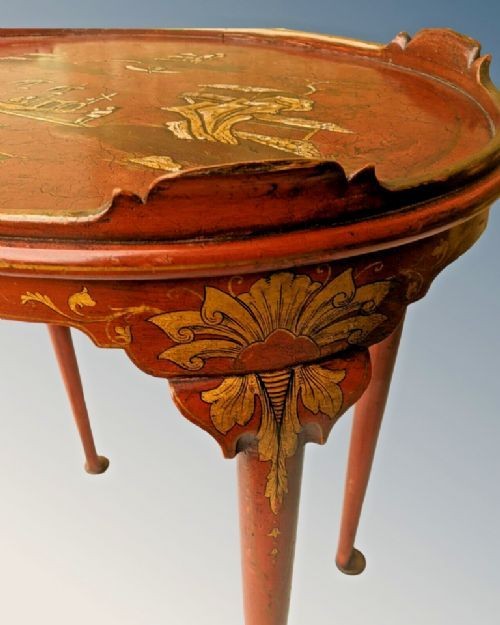 An oval antique red lacquer side table featuring hand-painted gold chinoiserie narrative scenes on the surface and slender legs. View III