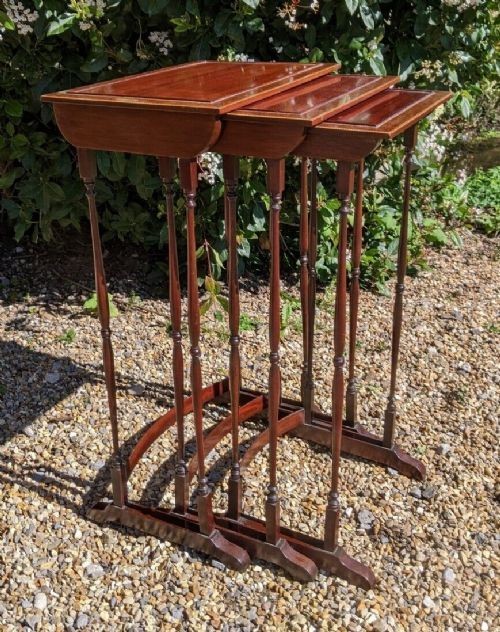 A set of three graduated Regency mahogany nesting tables featuring slender turned legs, curved stretchers, and sledge feet.
