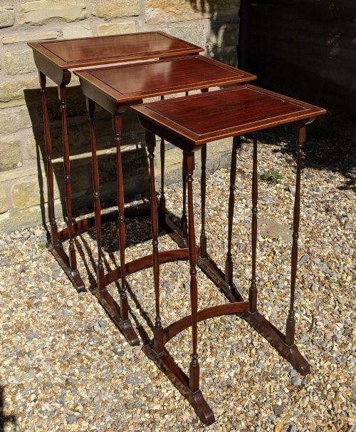 A set of three graduated Regency mahogany nesting tables featuring slender turned legs, curved stretchers, and sledge feet. View VII