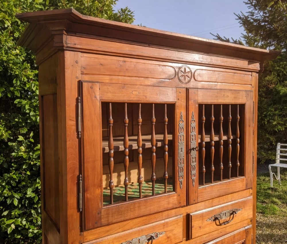 A French provincial fruitwood pantry cabinet featuring upper spindle-front doors, two central drawers with steel handles, lower solid panel doors, and carved cabriole feet. View IV