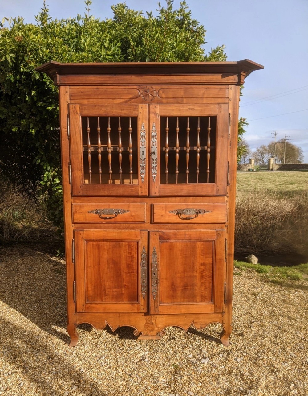 A French provincial fruitwood pantry cabinet featuring upper spindle-front doors, two central drawers with steel handles, lower solid panel doors, and carved cabriole feet. View V