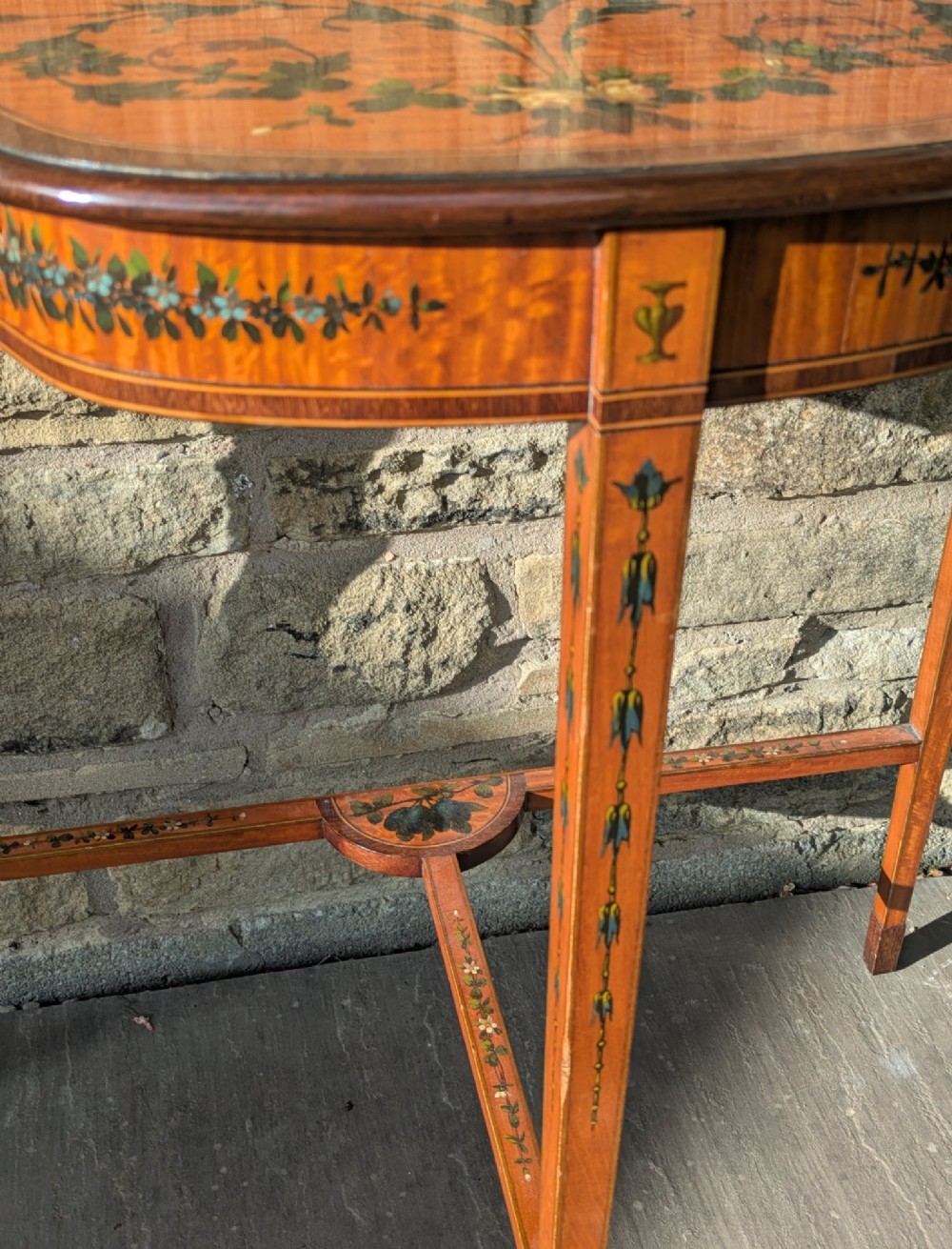 A Regency satinwood demilune side table featuring hand-painted floral garlands and slender tapered legs. View VII