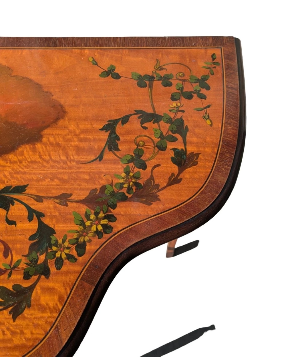 A Regency satinwood side table with a shaped top decorated with hand-painted floral swags and a central cherub medallion, supported by slim tapering legs. View VII