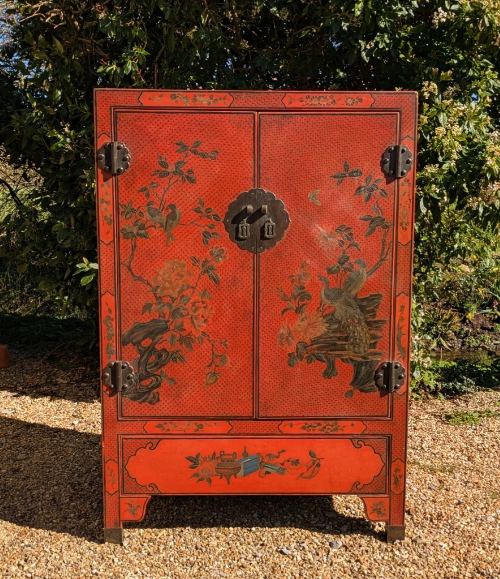 A red lacquered two-door Chinese cabinet decorated with black and gold hand-painted floral and bird motifs, supported on straight block feet and fitted with brass hardware. View III