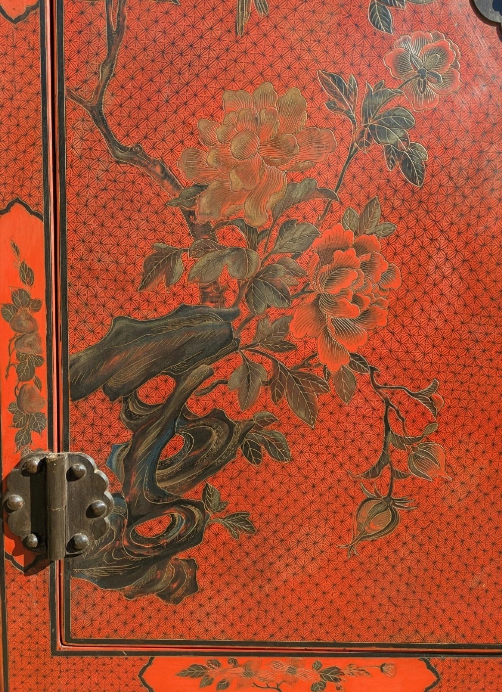 A red lacquered two-door Chinese cabinet decorated with black and gold hand-painted floral and bird motifs, supported on straight block feet and fitted with brass hardware. View V