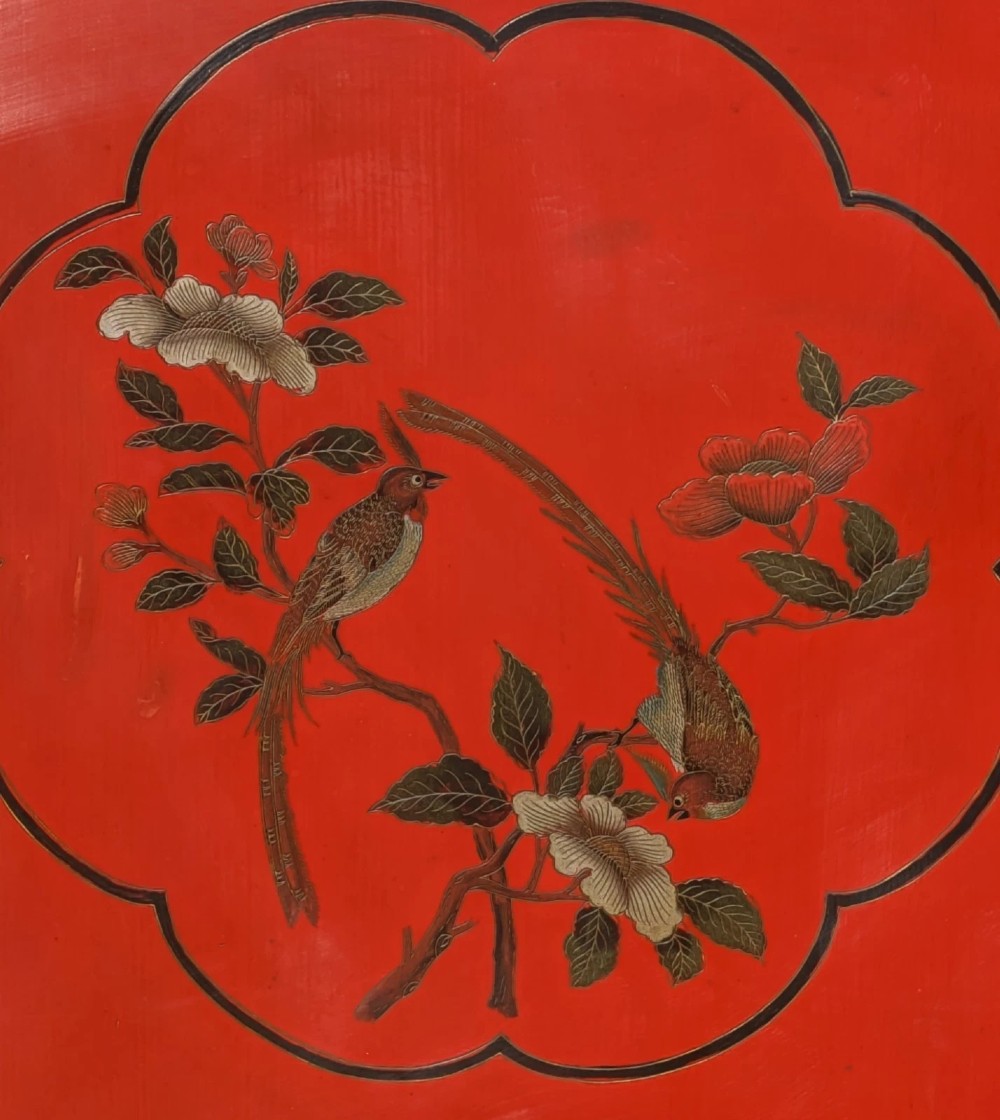 A red lacquered two-door Chinese cabinet decorated with black and gold hand-painted floral and bird motifs, supported on straight block feet and fitted with brass hardware. View VI