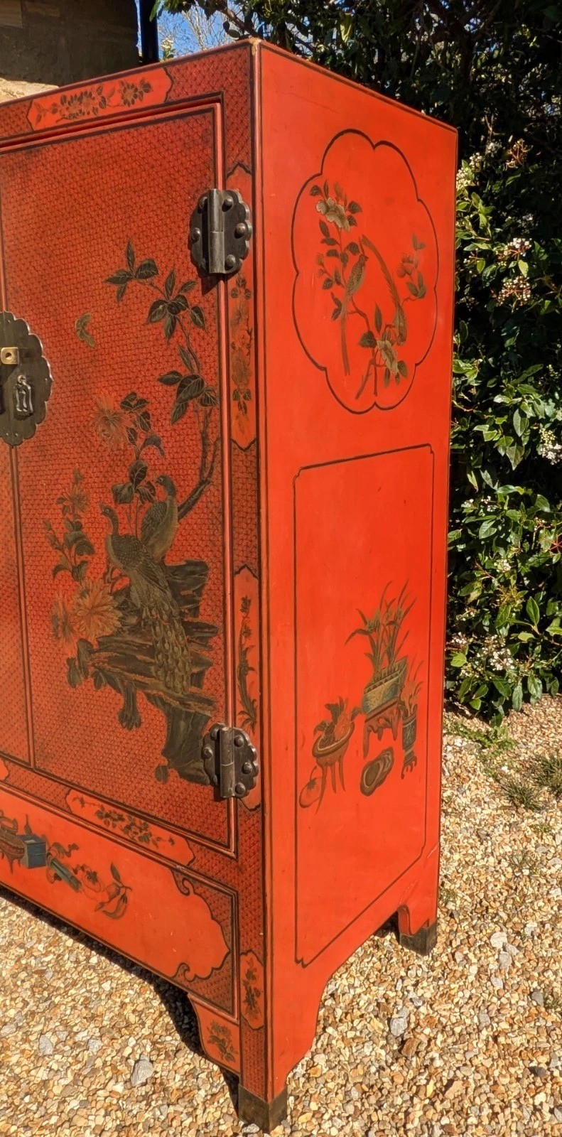 A red lacquered two-door Chinese cabinet decorated with black and gold hand-painted floral and bird motifs, supported on straight block feet and fitted with brass hardware. View VII
