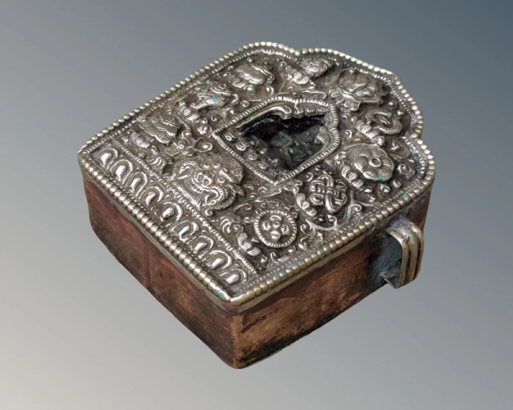 An arched Tibetan Gau prayer shrine featuring an intricately embossed silver metal front panel mounted on a copper casing with side loops. View VII