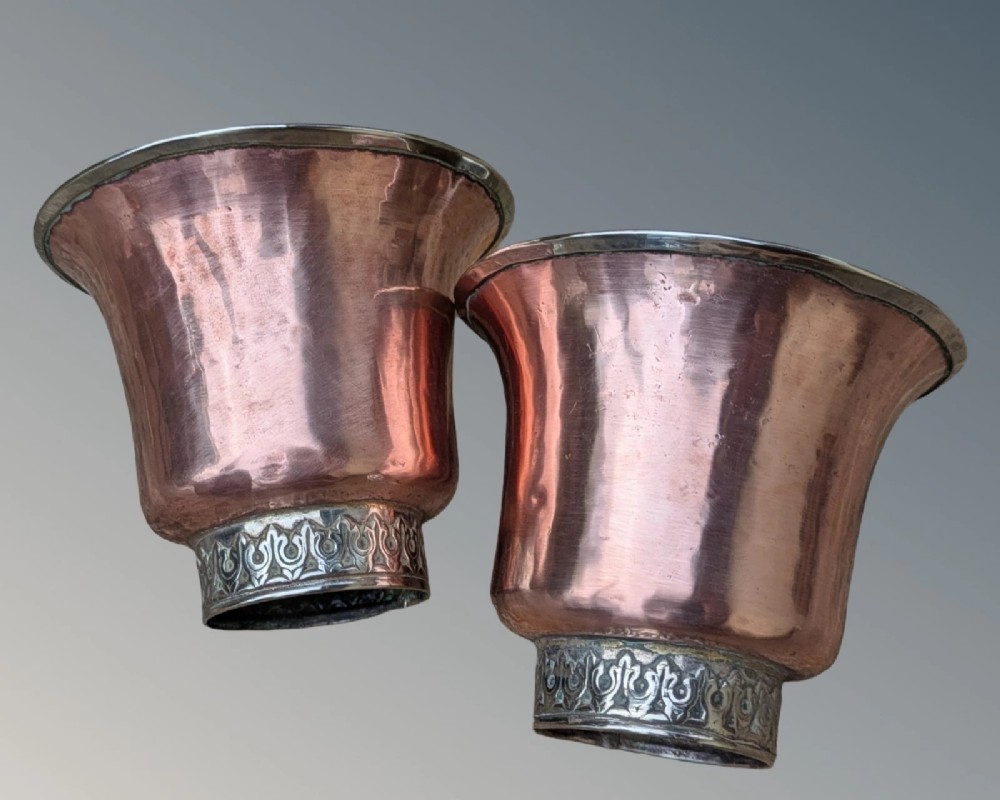 A pair of antique Tibetan flared drinking vessels with hand-hammered copper bodies, silver-lined interiors, and carved silver bases. View II