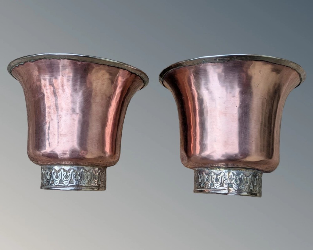 A pair of antique Tibetan flared drinking vessels with hand-hammered copper bodies, silver-lined interiors, and carved silver bases. View IV