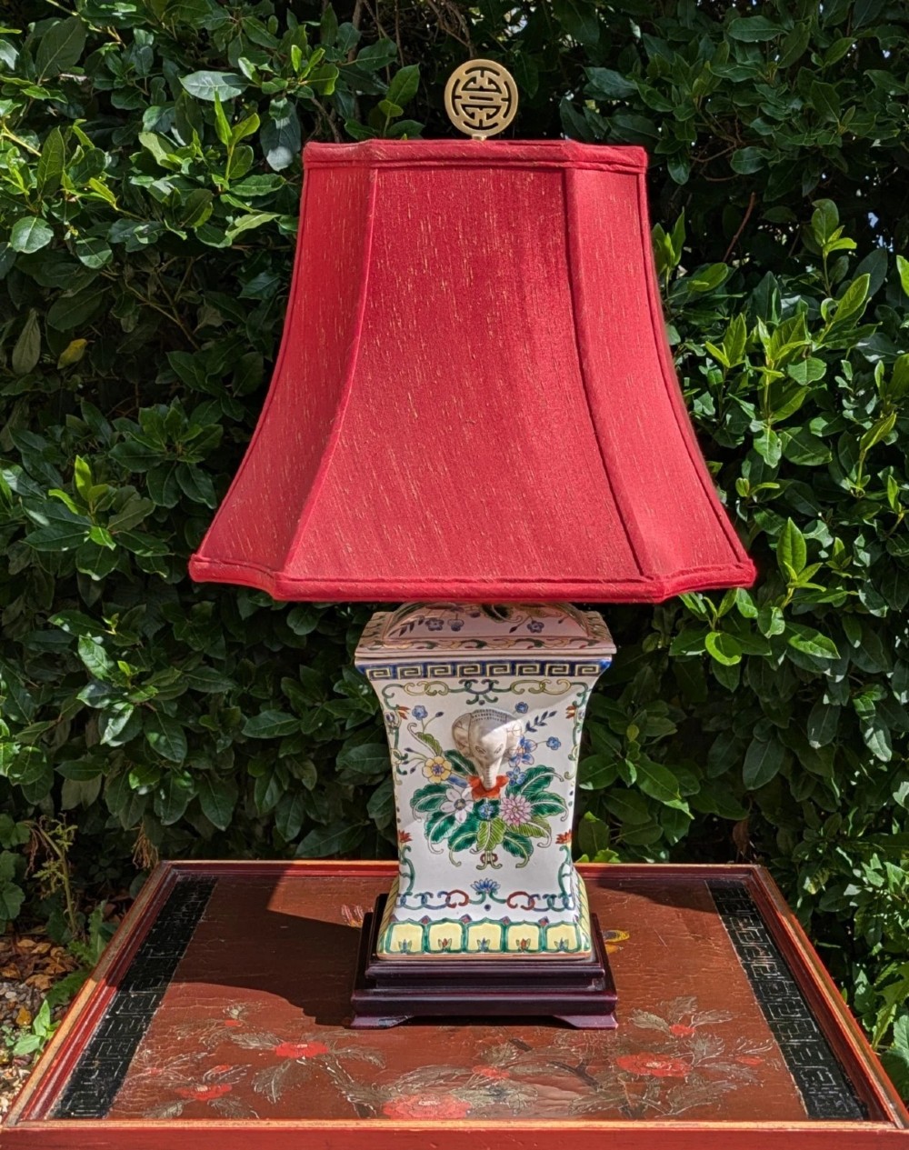 A pair of Chinese porcelain table lamps featuring hand-painted floral motifs and relief elephant details, topped with red silk shades. View III