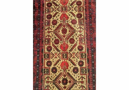 An antique Balouch tribal carpet featuring a cream central field with geometric diamond motifs surrounded by a deep red and navy blue geometric border. View III