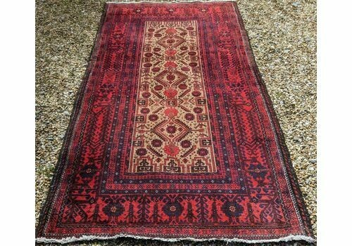 An antique Balouch tribal carpet featuring a cream central field with geometric diamond motifs surrounded by a deep red and navy blue geometric border. View V