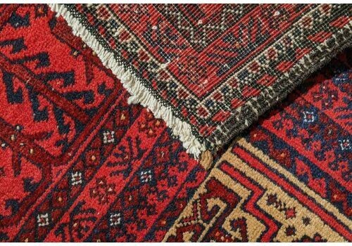 An antique Balouch tribal carpet featuring a cream central field with geometric diamond motifs surrounded by a deep red and navy blue geometric border. View VI