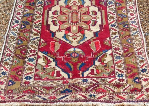 A hand-knotted Heriz carpet runner featuring geometric ivory medallions set against a deep red ground framed by multi-coloured decorative borders. View II