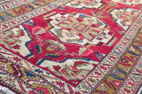 A hand-knotted Heriz carpet runner featuring geometric ivory medallions set against a deep red ground framed by multi-coloured decorative borders. View V