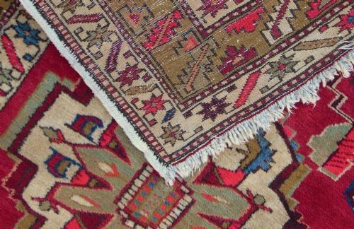A hand-knotted Heriz carpet runner featuring geometric ivory medallions set against a deep red ground framed by multi-coloured decorative borders. View VI