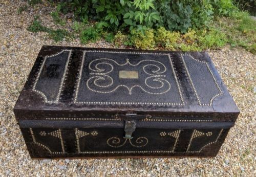 A dark brown leather rectangular coffer decorated with brass stud patterns, scrolling motifs, and a central metal latch. View IV