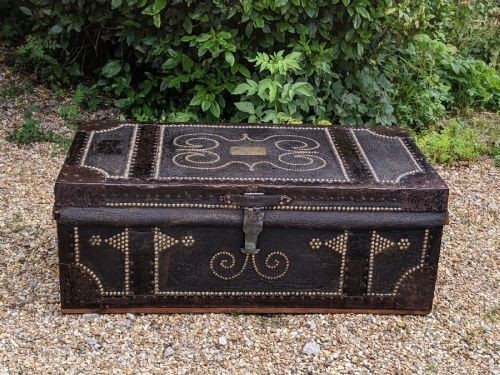A dark brown leather rectangular coffer decorated with brass stud patterns, scrolling motifs, and a central metal latch. View IX