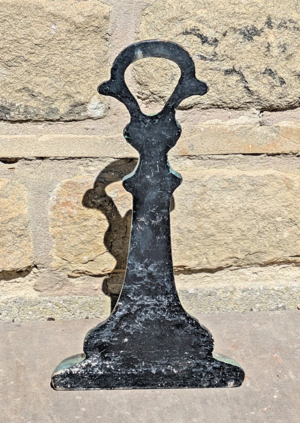 An Art Nouveau cast iron doorstop featuring organic whiplash foliage moulding, a looped carrying handle, and a distressed green finish. View V