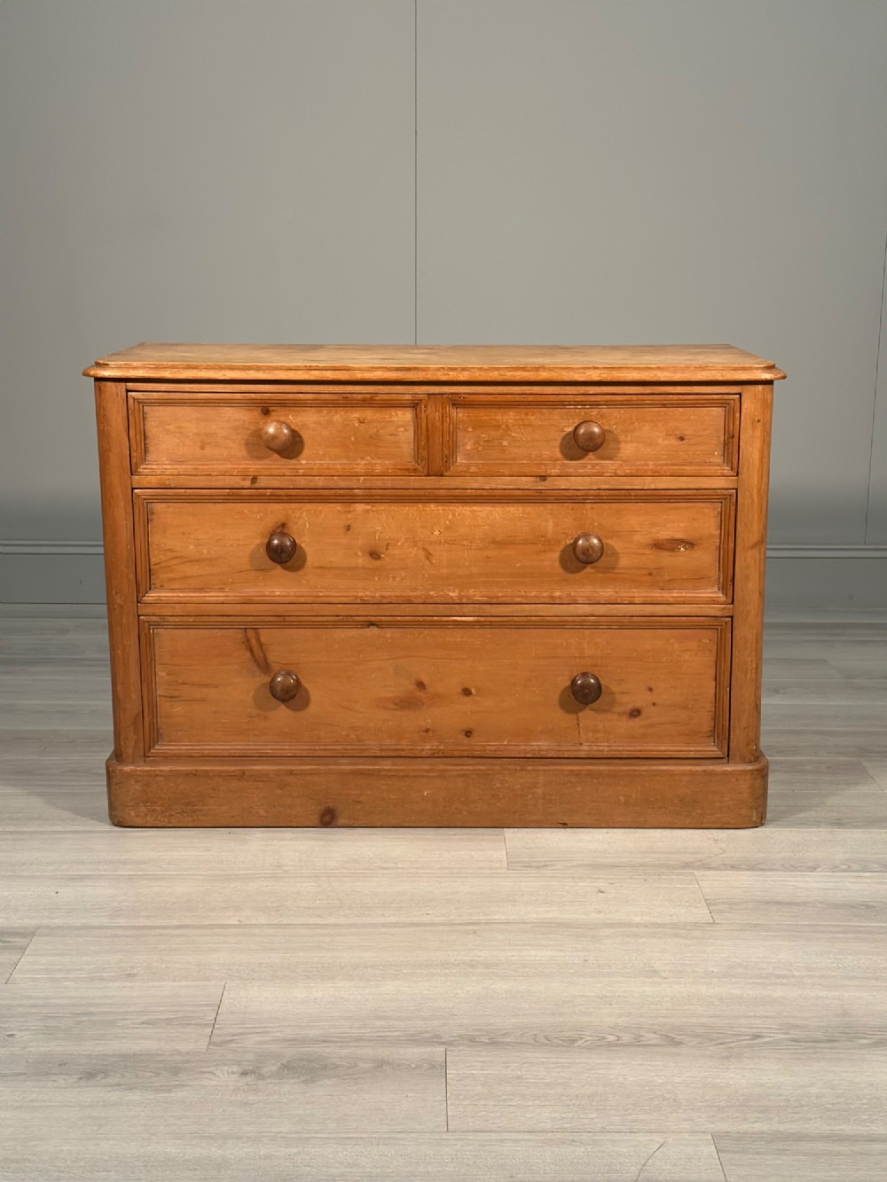 A nineteenth-century Victorian pine chest of drawers featuring a two-over-two drawer configuration, turned wooden knobs, and a solid plinth base.