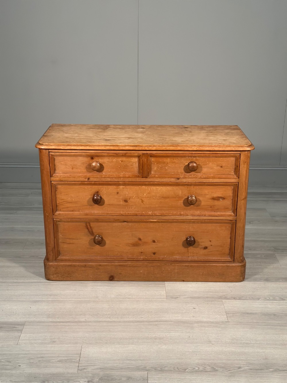 A nineteenth-century Victorian pine chest of drawers featuring a two-over-two drawer configuration, turned wooden knobs, and a solid plinth base. View II