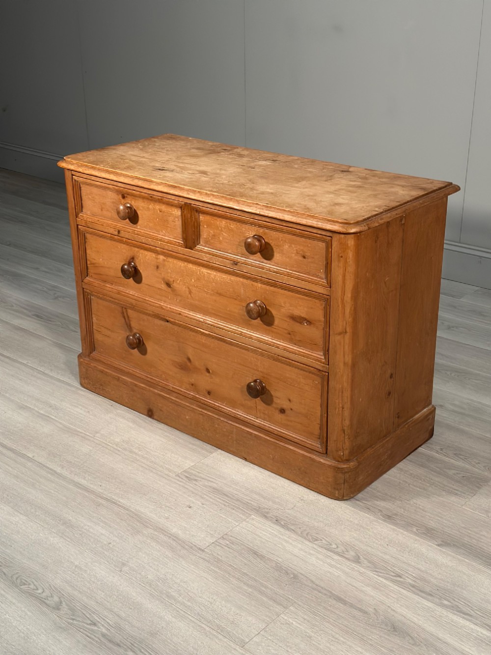 A nineteenth-century Victorian pine chest of drawers featuring a two-over-two drawer configuration, turned wooden knobs, and a solid plinth base. View III