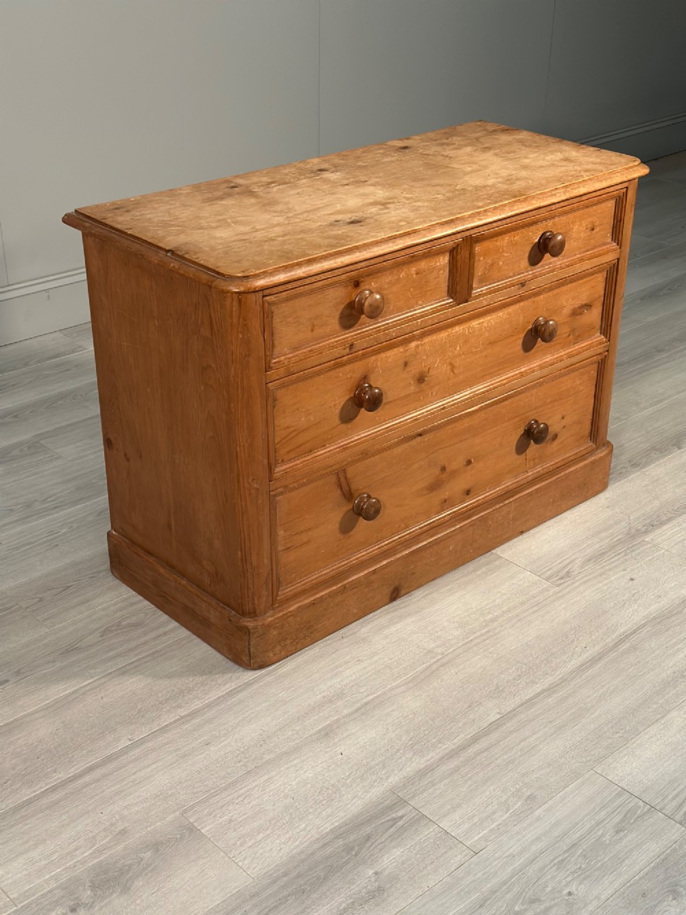 A nineteenth-century Victorian pine chest of drawers featuring a two-over-two drawer configuration, turned wooden knobs, and a solid plinth base. View IV