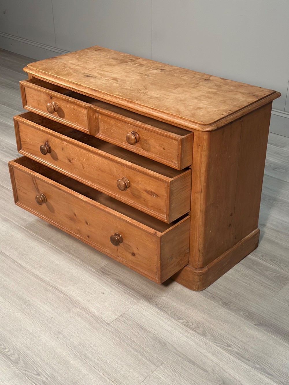 A nineteenth-century Victorian pine chest of drawers featuring a two-over-two drawer configuration, turned wooden knobs, and a solid plinth base. View V