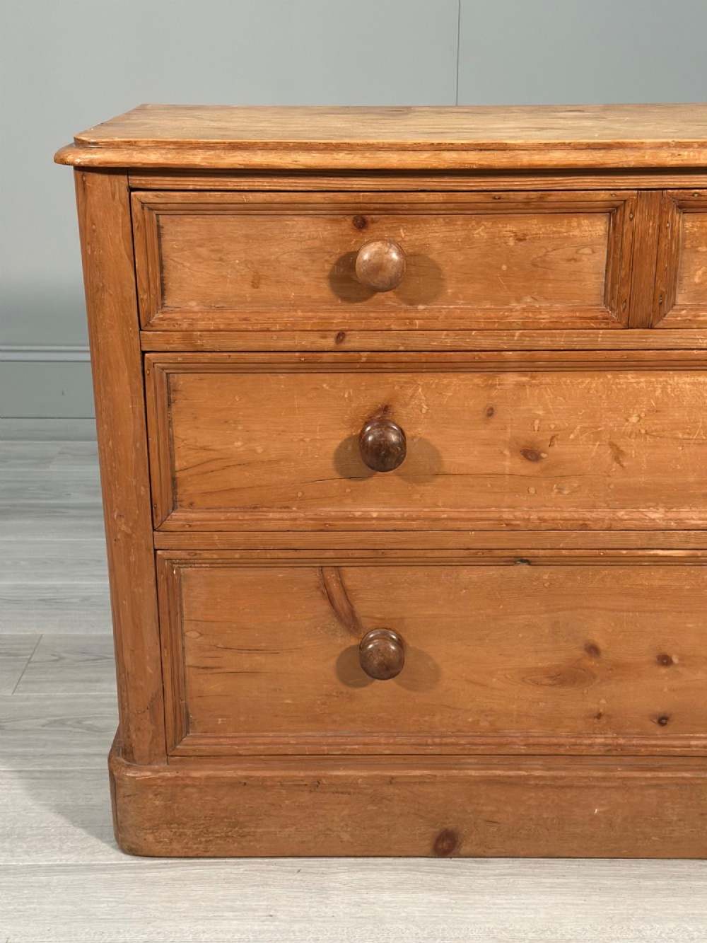 A nineteenth-century Victorian pine chest of drawers featuring a two-over-two drawer configuration, turned wooden knobs, and a solid plinth base. View VI