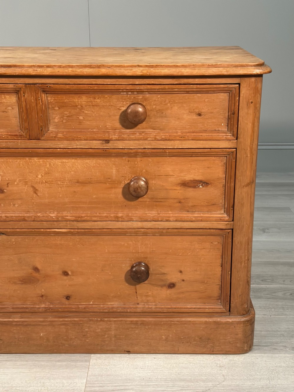 A nineteenth-century Victorian pine chest of drawers featuring a two-over-two drawer configuration, turned wooden knobs, and a solid plinth base. View VII