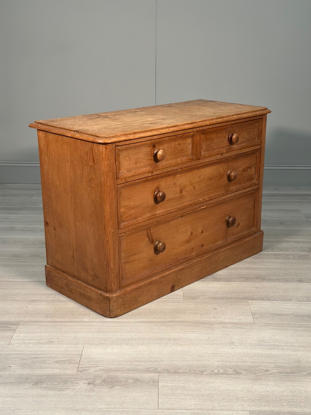 A nineteenth-century Victorian pine chest of drawers featuring a two-over-two drawer configuration, turned wooden knobs, and a solid plinth base. View VIII