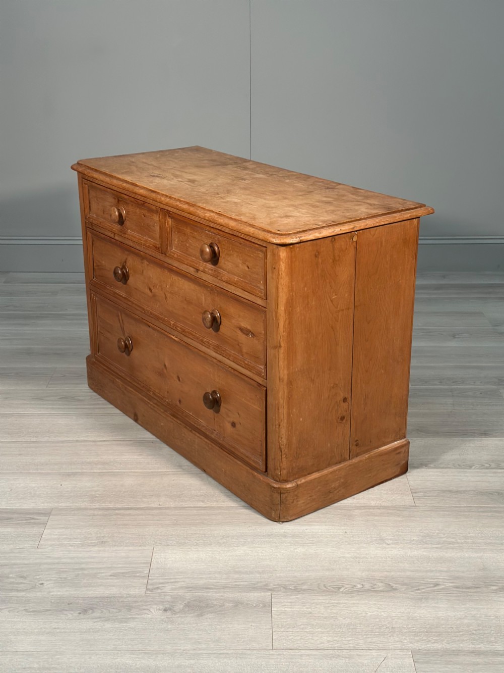 A nineteenth-century Victorian pine chest of drawers featuring a two-over-two drawer configuration, turned wooden knobs, and a solid plinth base. View IX