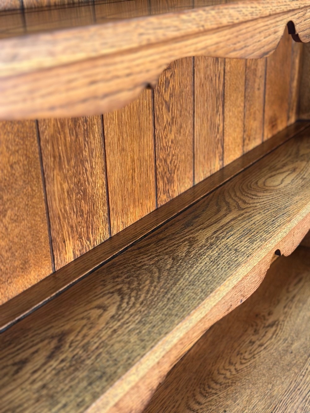 An antique oak Welsh dresser featuring a three-tier open plate rack above two moulded drawers with brass handles and a lower open potboard shelf supported by turned front legs. View X