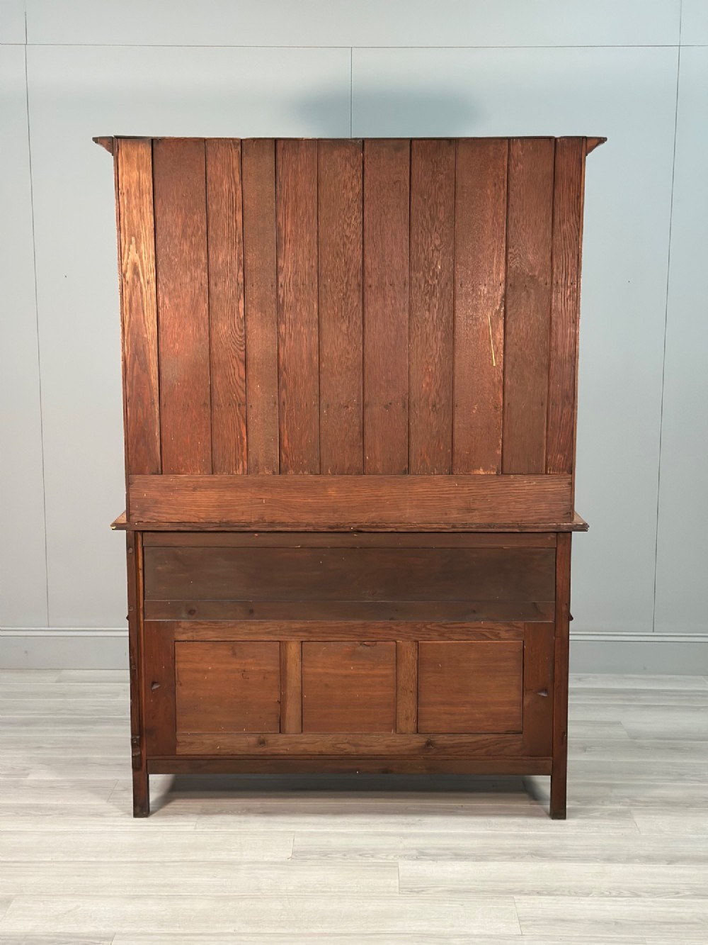 An antique oak Welsh dresser featuring a three-tier open plate rack above two moulded drawers with brass handles and a lower open potboard shelf supported by turned front legs. View XV