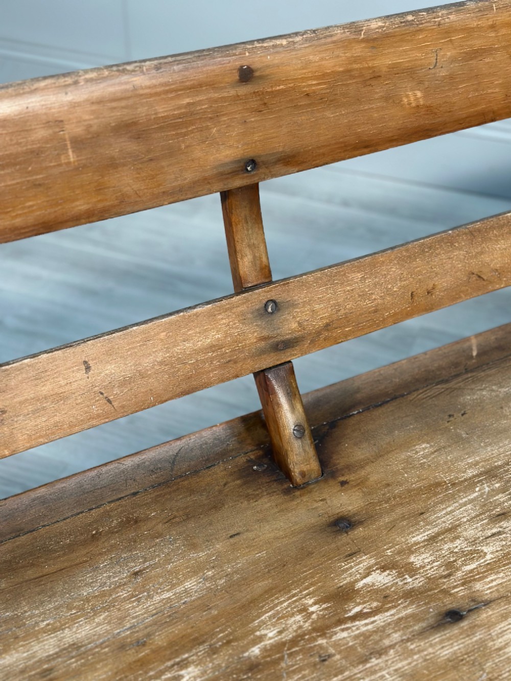 A long antique wooden rocking settle featuring open back slats, curved scroll armrests, and a solid plank seat resting on wooden rocking runners. View III