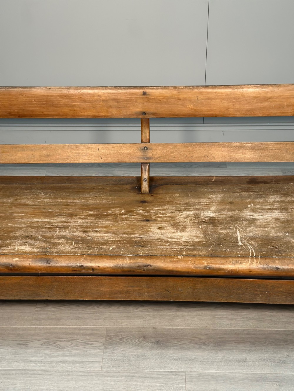 A long antique wooden rocking settle featuring open back slats, curved scroll armrests, and a solid plank seat resting on wooden rocking runners. View VIII