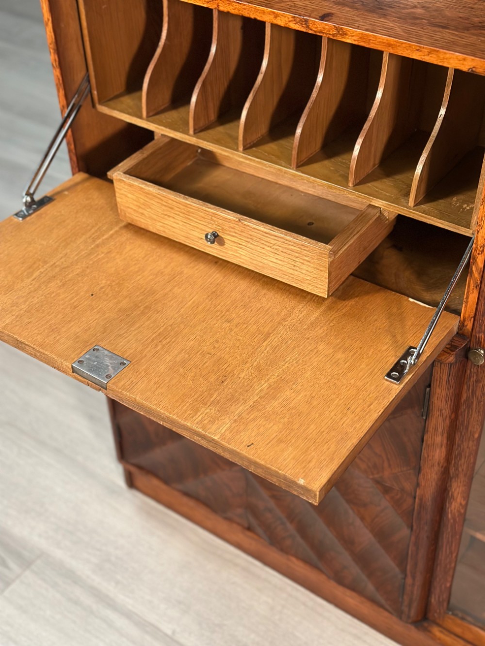 An Art Deco oak bureau bookcase featuring an open top shelf, drop-down writing flap, a glazed side cabinet, and lower cupboards with geometric diamond veneer. View IV