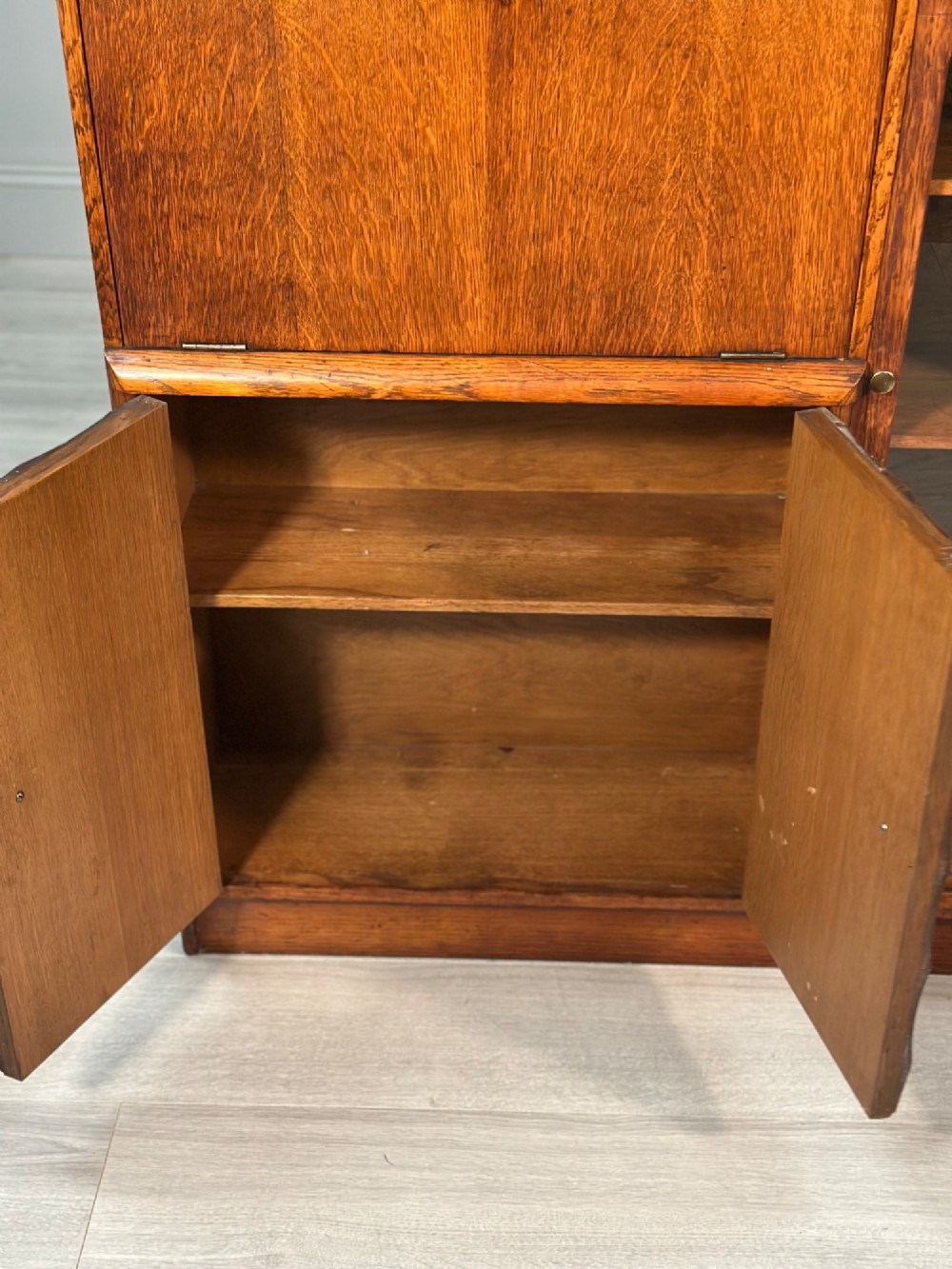 An Art Deco oak bureau bookcase featuring an open top shelf, drop-down writing flap, a glazed side cabinet, and lower cupboards with geometric diamond veneer. View VI