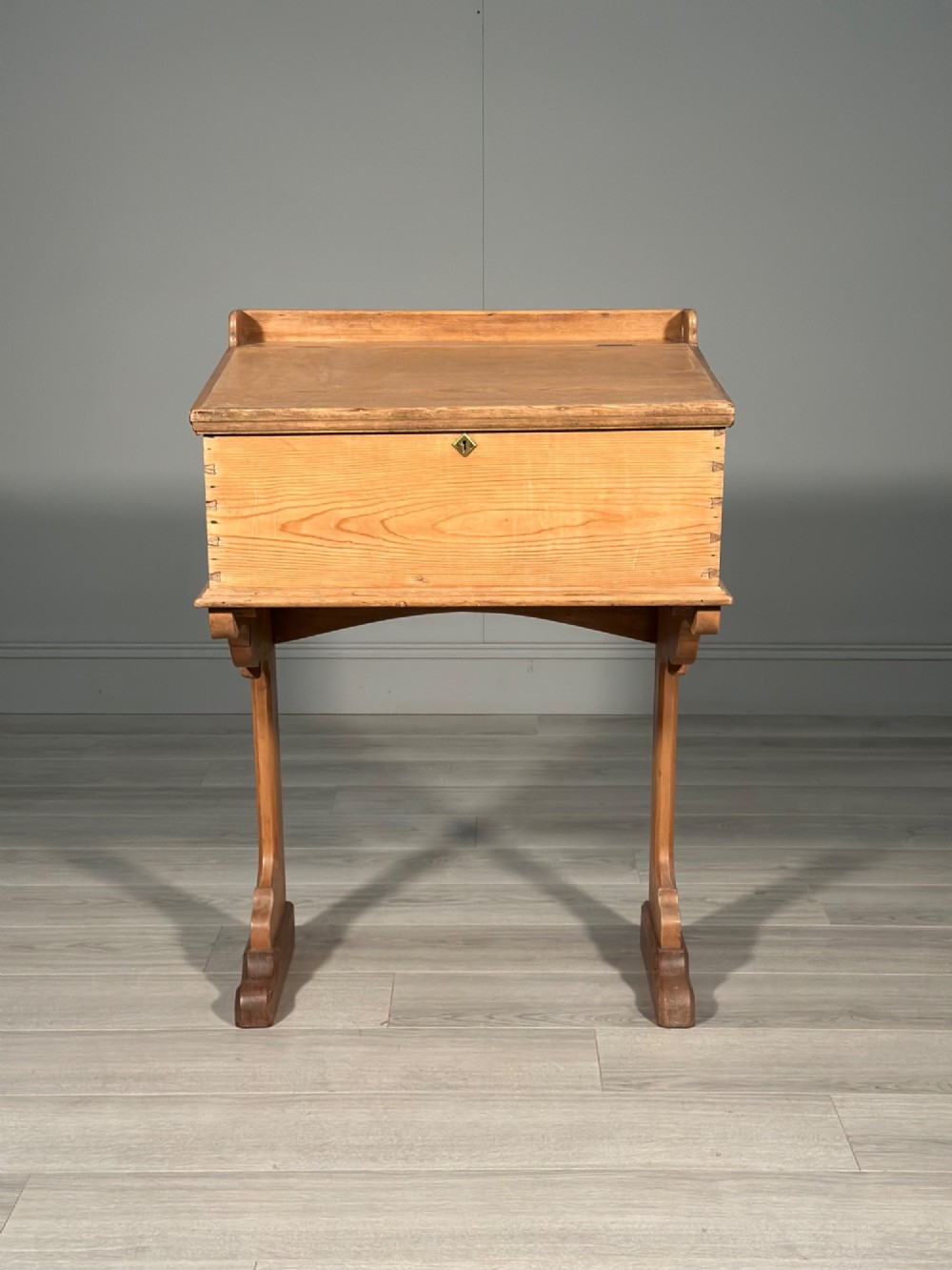A Victorian pine school desk featuring a slanted hinged lid, dovetail joinery, shaped side supports, and a raised back gallery. View II
