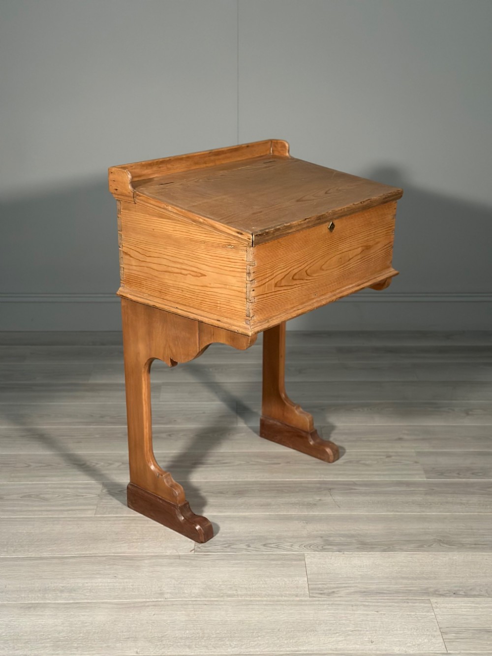 A Victorian pine school desk featuring a slanted hinged lid, dovetail joinery, shaped side supports, and a raised back gallery. View V