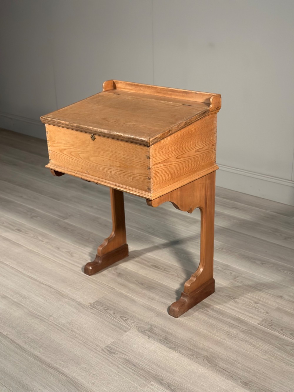 A Victorian pine school desk featuring a slanted hinged lid, dovetail joinery, shaped side supports, and a raised back gallery. View X