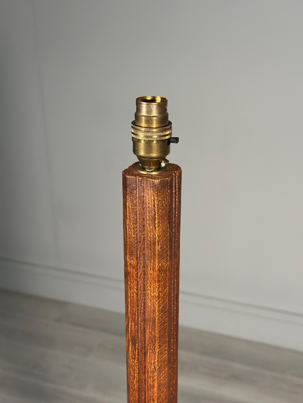 An Arts and Crafts solid oak standard lamp featuring a faceted tapered column on an octagonal base with brass bulb holder. View IV