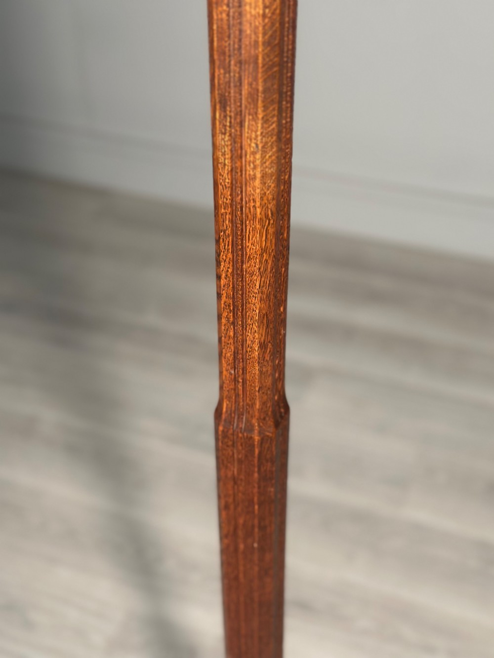 An Arts and Crafts solid oak standard lamp featuring a faceted tapered column on an octagonal base with brass bulb holder. View VI