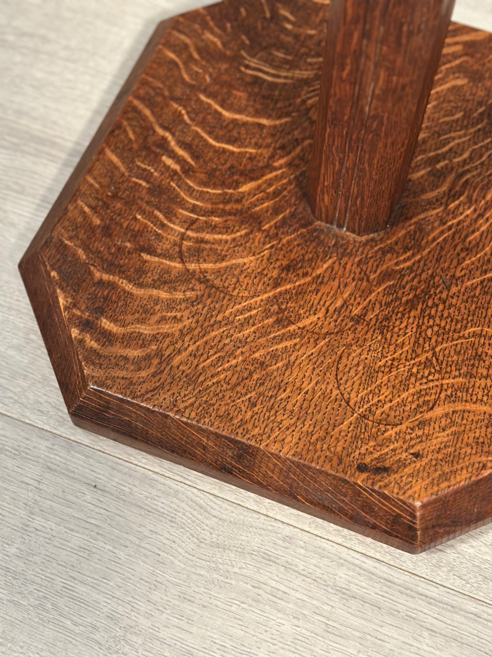 An Arts and Crafts solid oak standard lamp featuring a faceted tapered column on an octagonal base with brass bulb holder. View VII