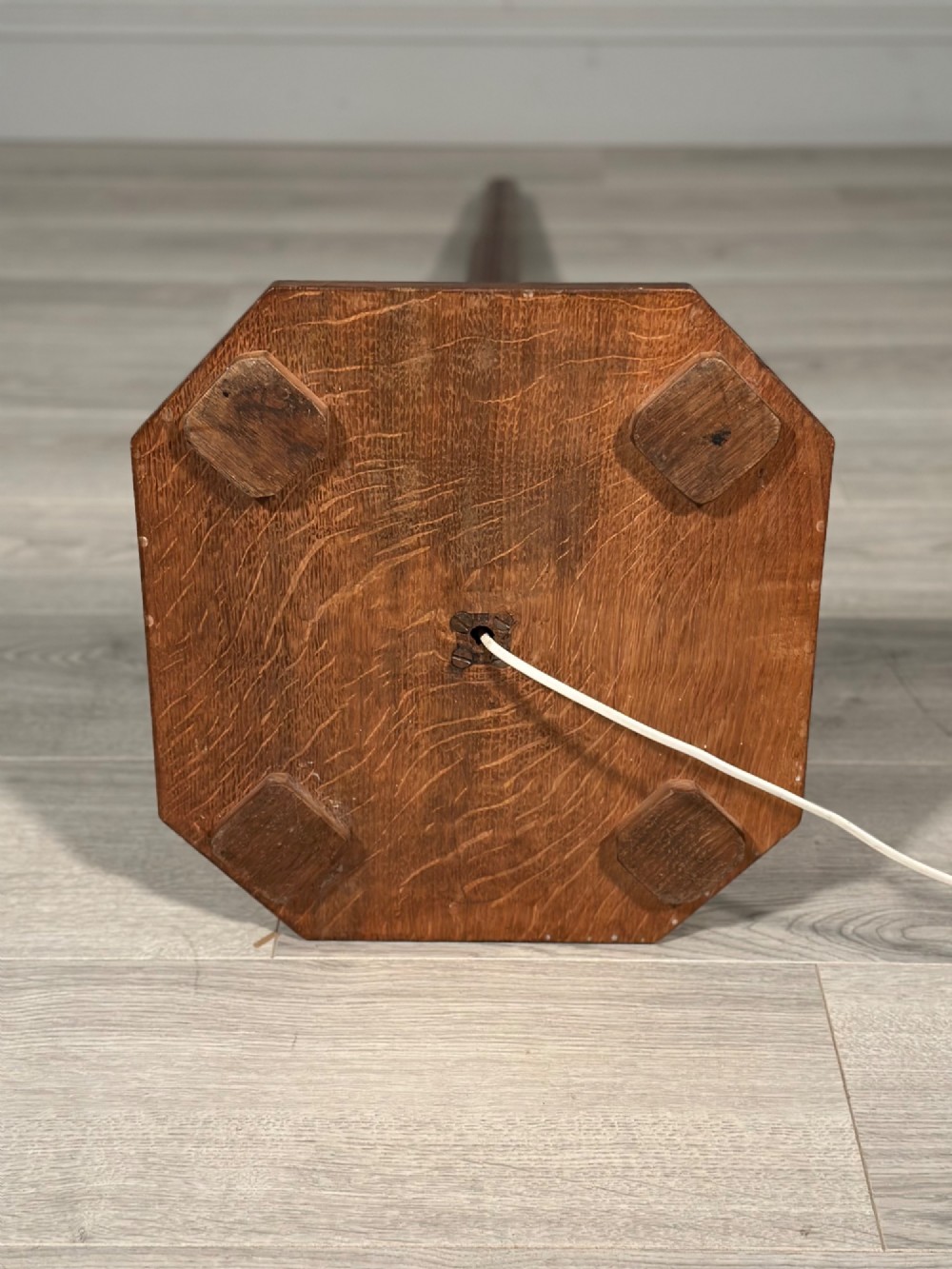 An Arts and Crafts solid oak standard lamp featuring a faceted tapered column on an octagonal base with brass bulb holder. View IX