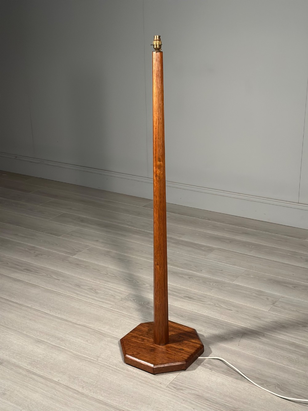 A tall Arts and Crafts solid oak standard lamp featuring a faceted stem mounted on an octagonal base with a brass light socket. View III