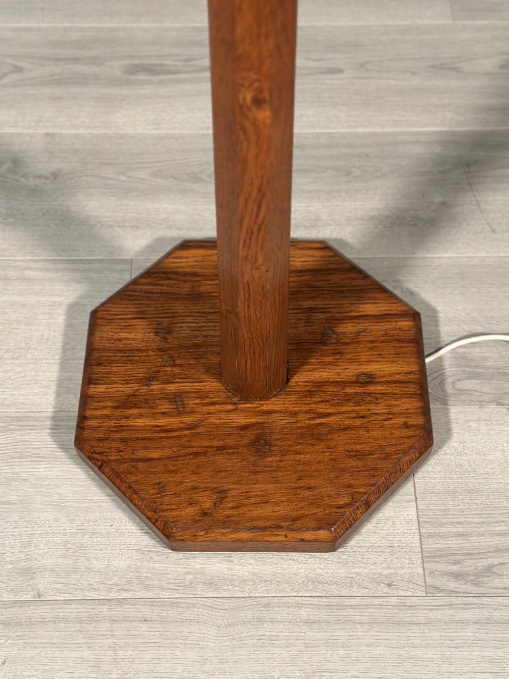 A tall Arts and Crafts solid oak standard lamp featuring a faceted stem mounted on an octagonal base with a brass light socket. View IV